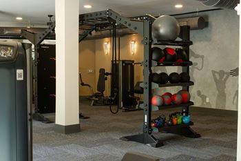 A gym with a weight rack and a rowing machine.